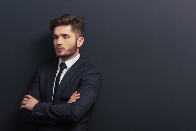 Handsome young student in classic suit is looking away. Copyspace background