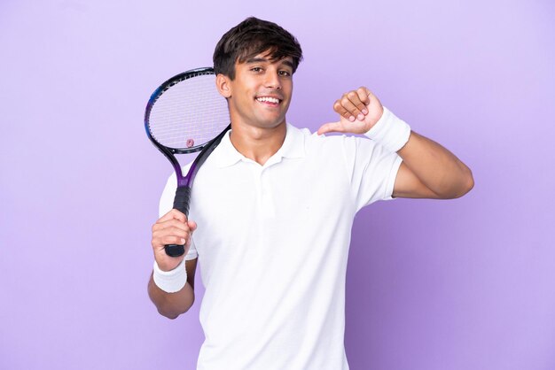 Handsome young tennis player man isolated on ocher background proud and self-satisfied