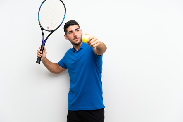 Handsome young tennis player man over isolated white wall 