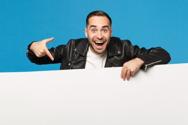 Photo handsome young unshaven man hold big white empty blank billboard for promotional content isolated on blue wall background studio portrait. people sincere emotions lifestyle concept. mock up copy space