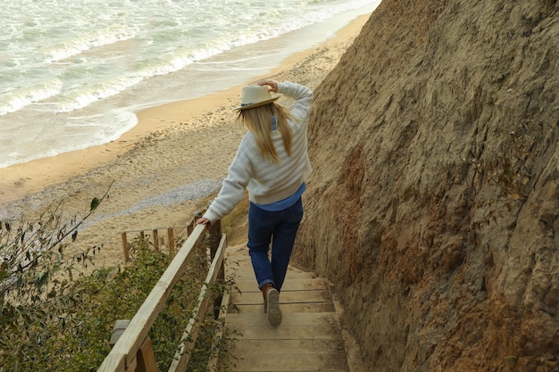 Handsome young woman on wooden steps against sandy beach