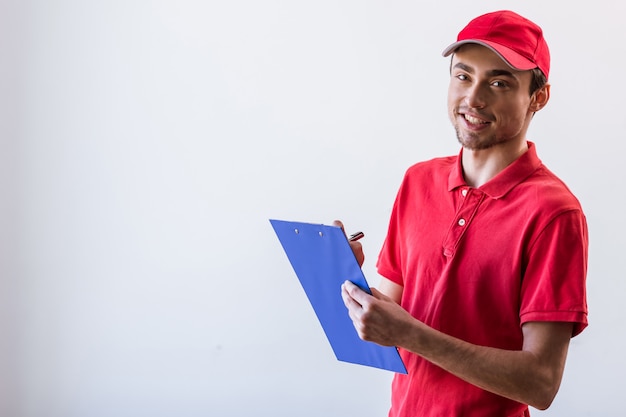 Handsome young worker in red t-shirt and cap smiling.