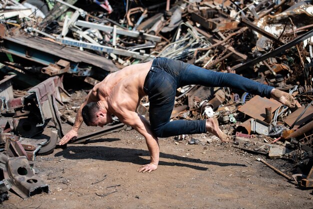 Foto allenamento dell'uomo delle flessioni in verticale alla discarica industriale