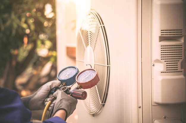 Handtechnicus die de spruitstukmeter gebruikt die de koelmiddelairconditioner controleert