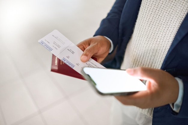 Handtelefoon en paspoort met ticket voor reisschema of vluchttijden controleren op mobiele app op een luchthaven Hand van bedrijfsmedewerker met smartphonescherm of ID-document voor reis of reis