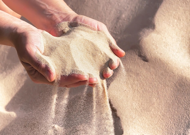 Handvol zand in de handen van de vrouw selectieve aandacht Het zand stroomt uit vrouwelijke handen