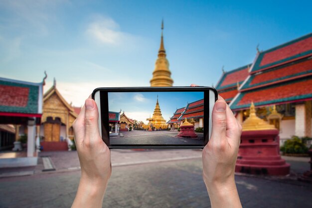 handvrouw die foto nemen bij wat phratad haripunchai in lamphun, Thailand.