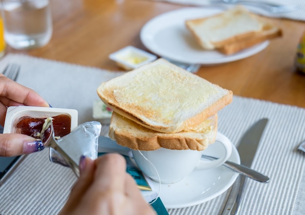 Handvrouw met brood met fruitjam op houten tafel