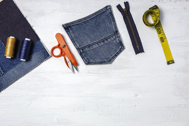 Handwerk, kledingreparatie. Gescheurde jeans naaiaccessoires van bovenaf. plat leggen