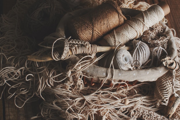 Handwerken, macramé, breien. Garen en draad van natuurlijke kleuren in een rieten mand. Vrouwenhobby.