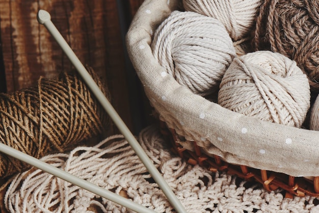 Handwerken, macramé, breien. Garen en draad van natuurlijke kleuren in een rieten mand. Vrouwenhobby.