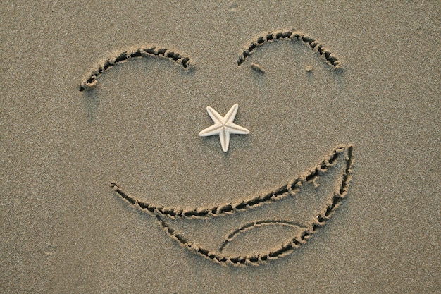 Handwrited face on the sand at the beach