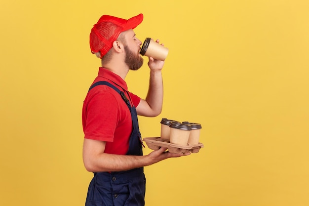 Фото Умелому человеку, стоящему с одноразовыми стаканчиками и пьющему горячий напиток, нужна энергия для продолжения работы