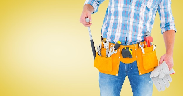 Handy man standing with tools against yellow background