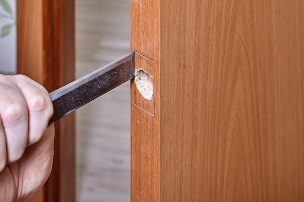 Handyman beitelt hout langs de lip zodat de plaatvergrendeling erin kan schuiven.