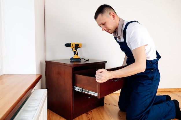 Photo handyman in blue uniform works with electricity automatic screwdriver. house renovation conception.