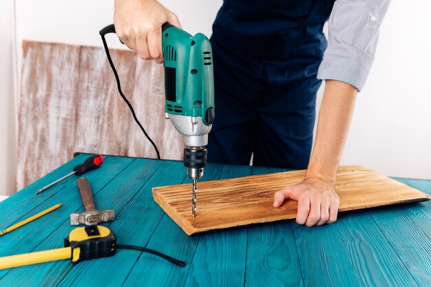 Handyman in blue uniform works with electricity automatic screwdriver