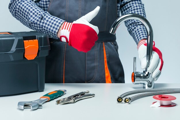 Handyman holding faucet and showing thumb up. Plumber.