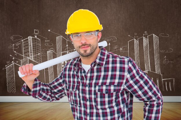 Handyman holding rolled up blueprint against room with wooden floor