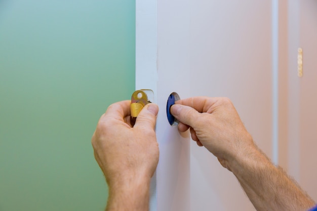 Handyman installing the door lock in worker's hands installing new door locker