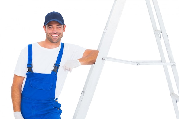 Handyman in overalls leaning on ladder