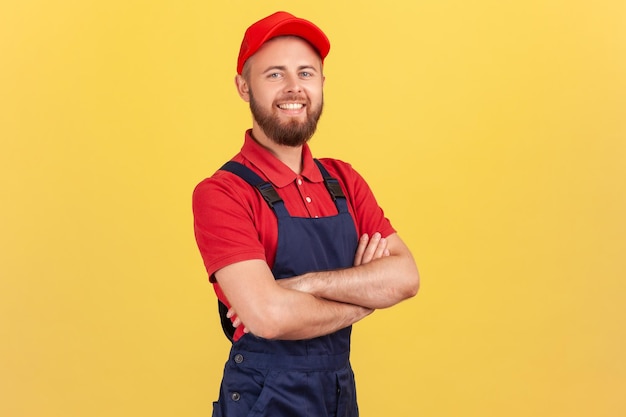 Handyman in overalls standing with crossed arms looking at camera profession of service industry