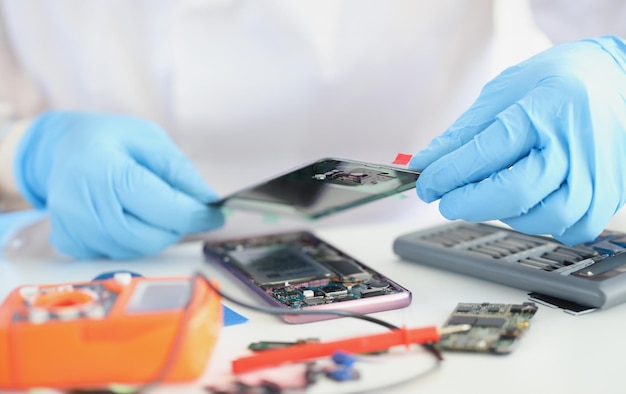 Handyman repairing broken smartphone, put cover on top, worker wear gloves