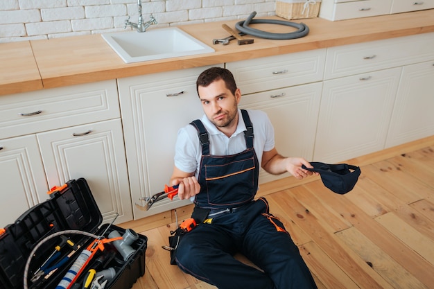 Handyman sit on floor in kitchen