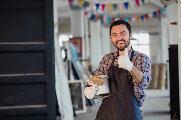 Handyman using brush in his workshop with thumb up