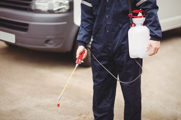 Handyman with insecticide standing in front of his van