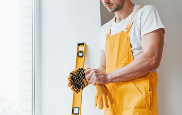 Foto tuttofare in uniforme gialla che si prepara per il lavoro all'interno concezione di ristrutturazione della casa