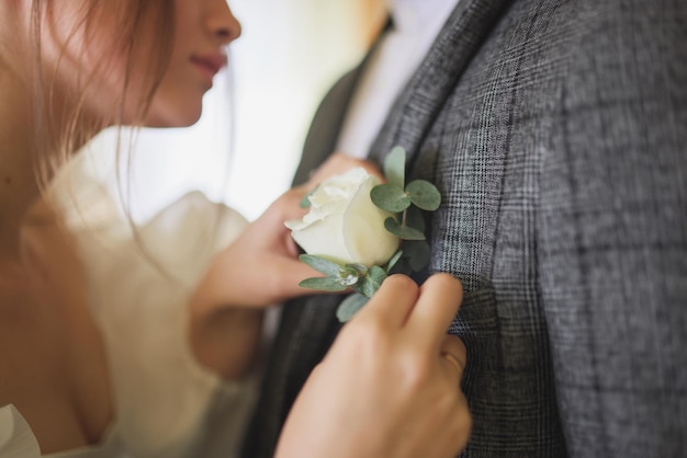 Hang of a bride adjusting boutonniere on grooms jacket