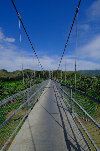 hangbrug met staalconstructie en staalkabels. brug in tropisch landschap. blauwe lucht