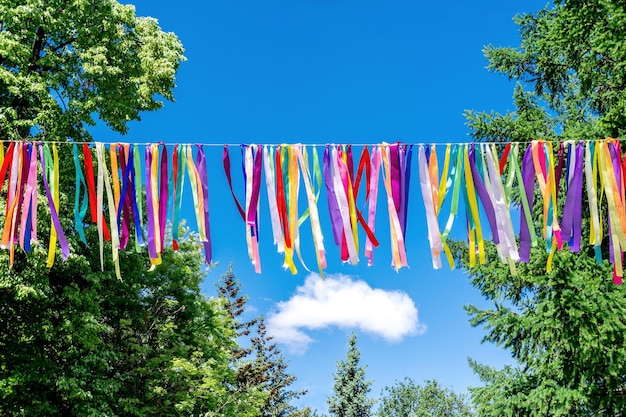 Foto hangende kleurrijke linten op de achtergrond van bomen en blauwe lucht decoratieve decoratie