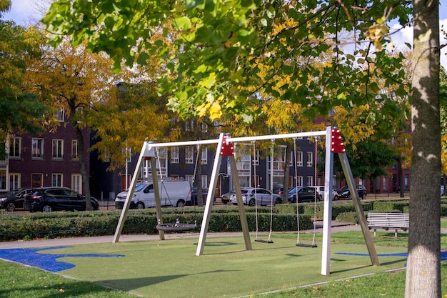 Hangende moderne schommel op de speelplaats Zachte grasmat