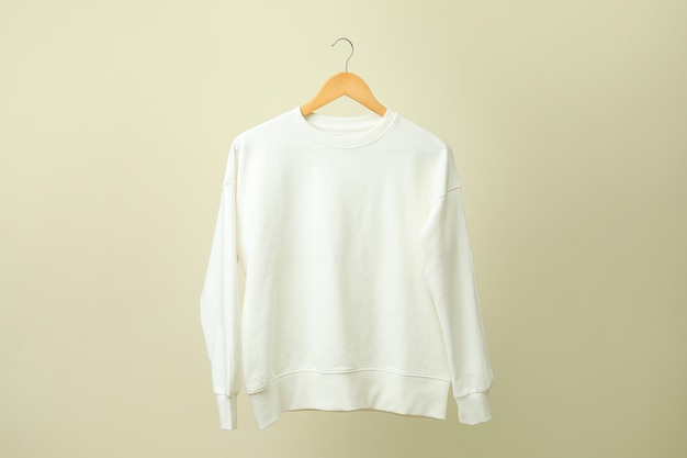 Hanger met wit sweatshirt tegen beige oppervlak