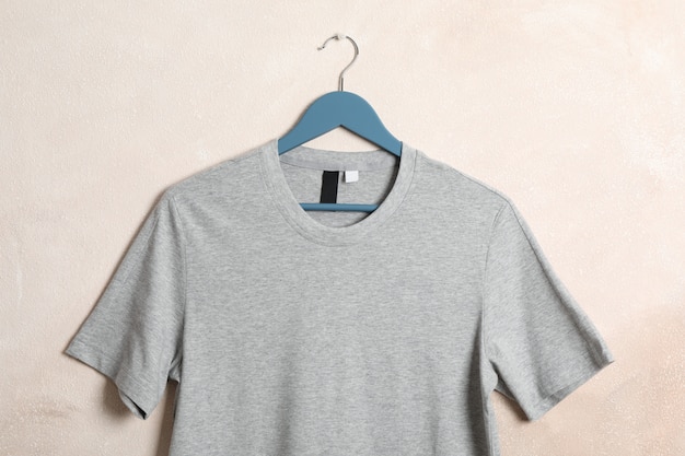 Hanger with blank gray t-shirt on light brown