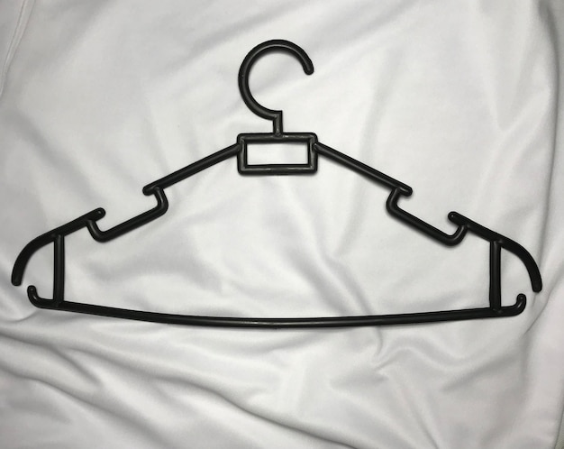 A hanger with a hanger on it is on a white cloth.
