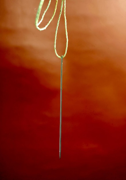 hanging big sewing needle on a rope on brown background