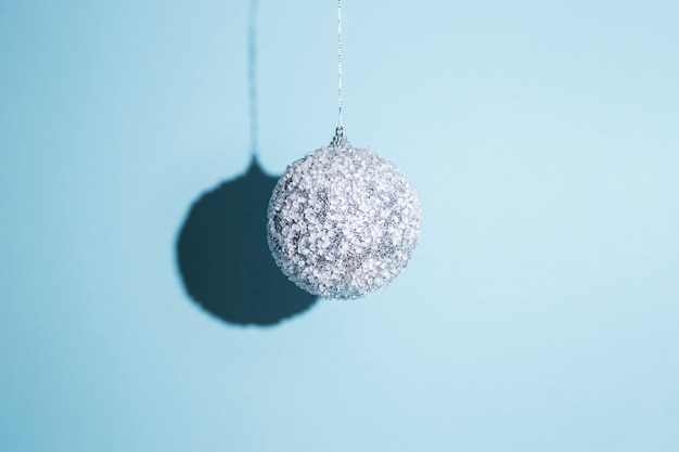 Hanging Christmas ball on a blue background. Hard light.