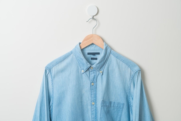 hanging jean shirt with wood hanger on wall