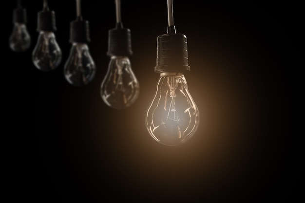 Hanging light bulbs with glowing one on dark background