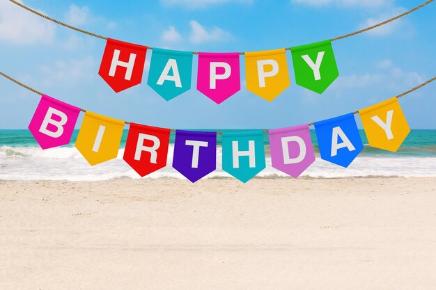 Banner di feste multicolori da appendere con un cartello di buon compleanno su un rendering 3d di una spiaggia di mare o oceano