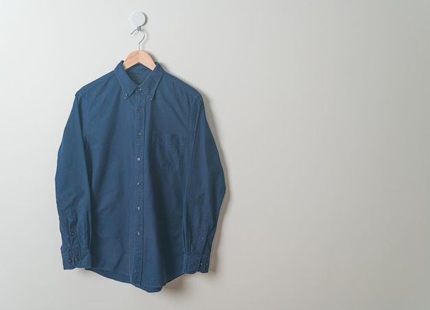 hanging navy shirt with wood hanger on wall