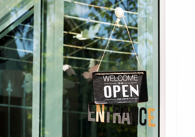 Hanging sign with message WELCOME OPEN on glass door at coffee shop