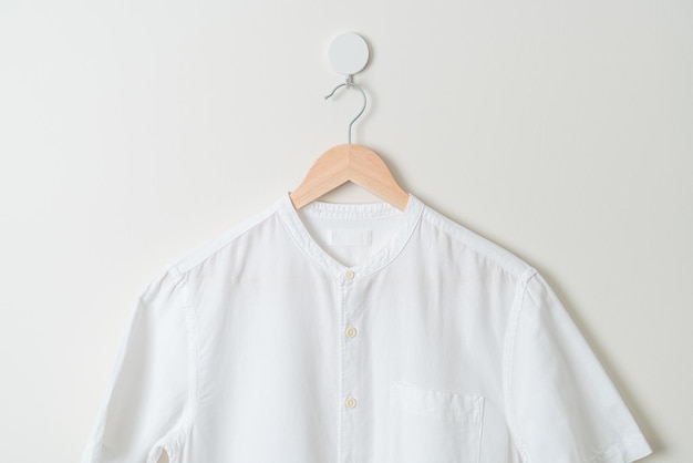 hanging white shirt with wood hanger on wall