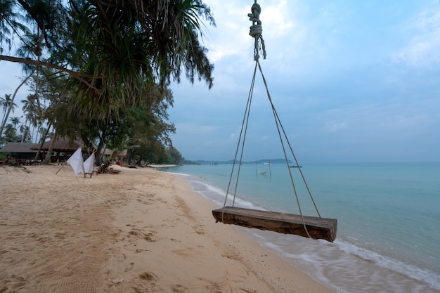 Hanging wooden timber swing at blue sea beach, Tapao beach in Koh Kood island, Thailand