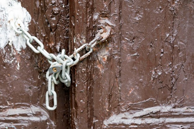 Hangslot met een ketting op een bruin geschilderde deur close-up achtergrond