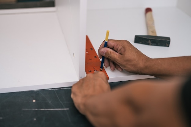 Hans of a man marking the point where make holes for screws in a piece of furniture