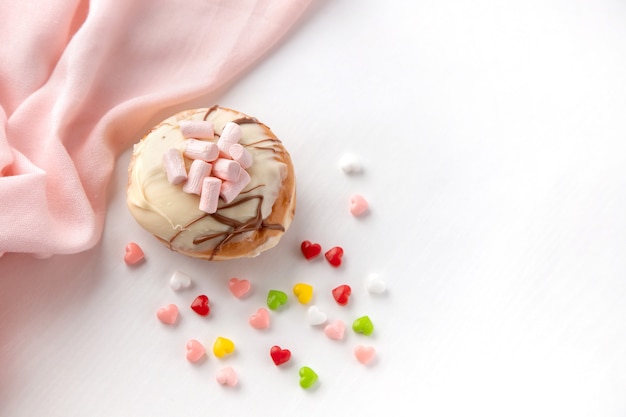 Hanukkah donut and colorful candies on a white table